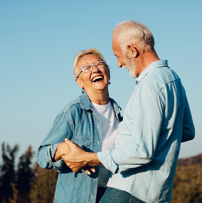 Older couple smiling and laughing with dental implants in San Jose
