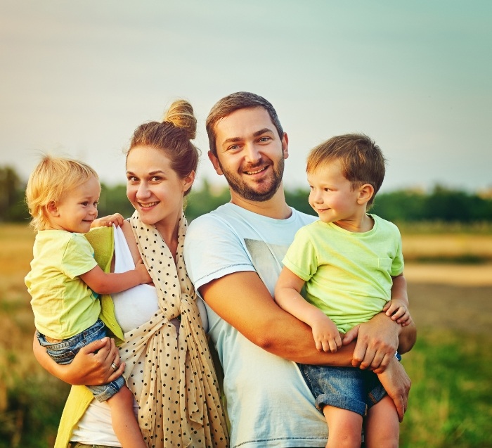 Man and woman holding children in a field