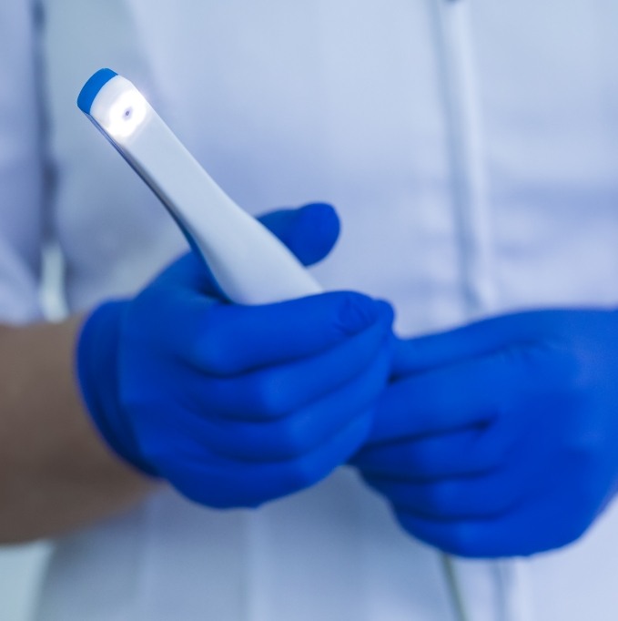 Gloved hands holding an intraoral camera