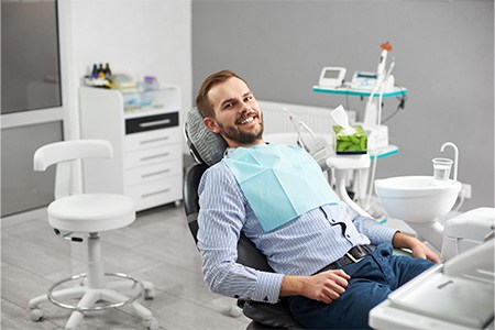 Bearded man sitting back in dental chair and smiling