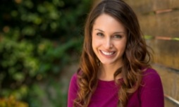 Woman smiling next to a brick wall