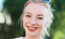 Woman with blonde hair sunglasses and braces