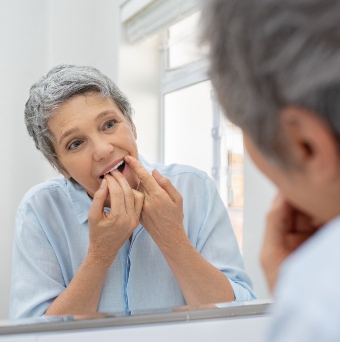 Senior woman checking teeth in mirror