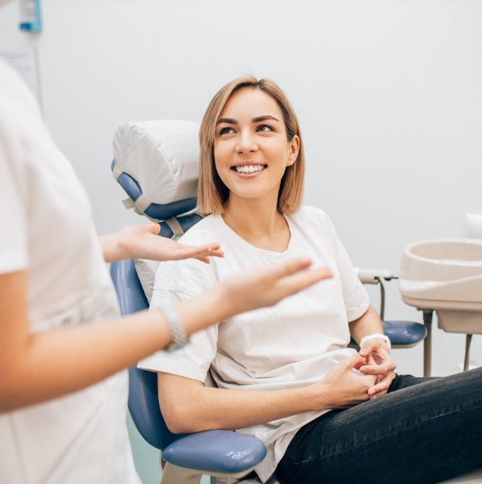 Female patient smiling and looking up at dentist