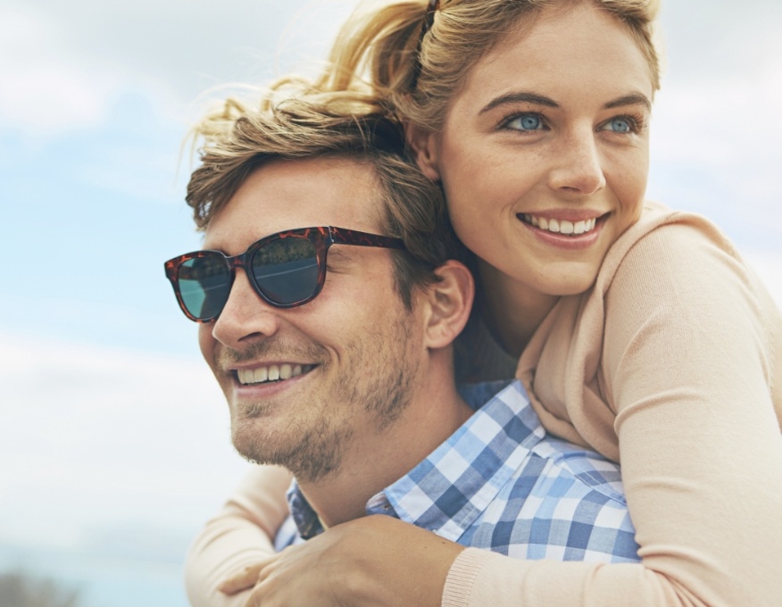 Man with sunglasses giving woman a piggyback ride