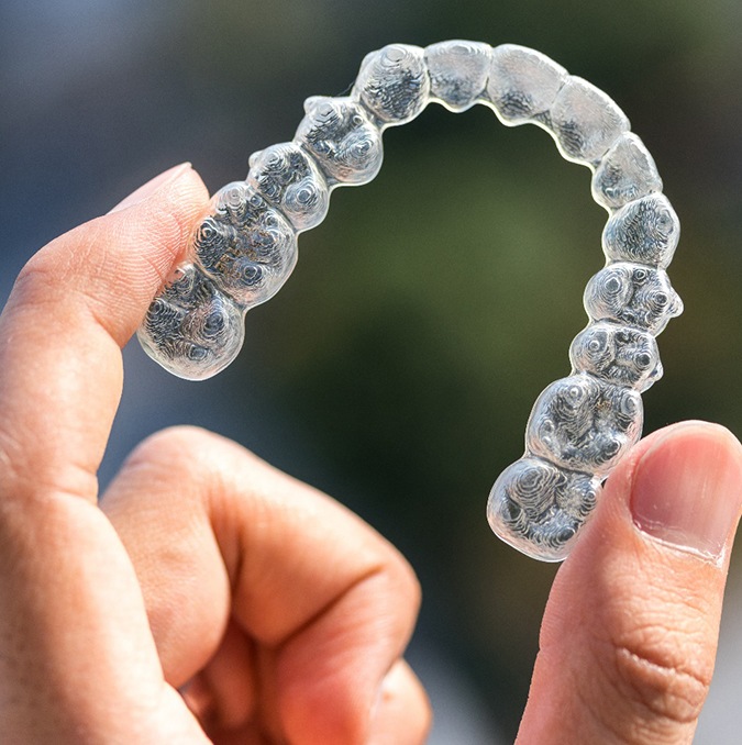 Someone holding an Invisalign aligner