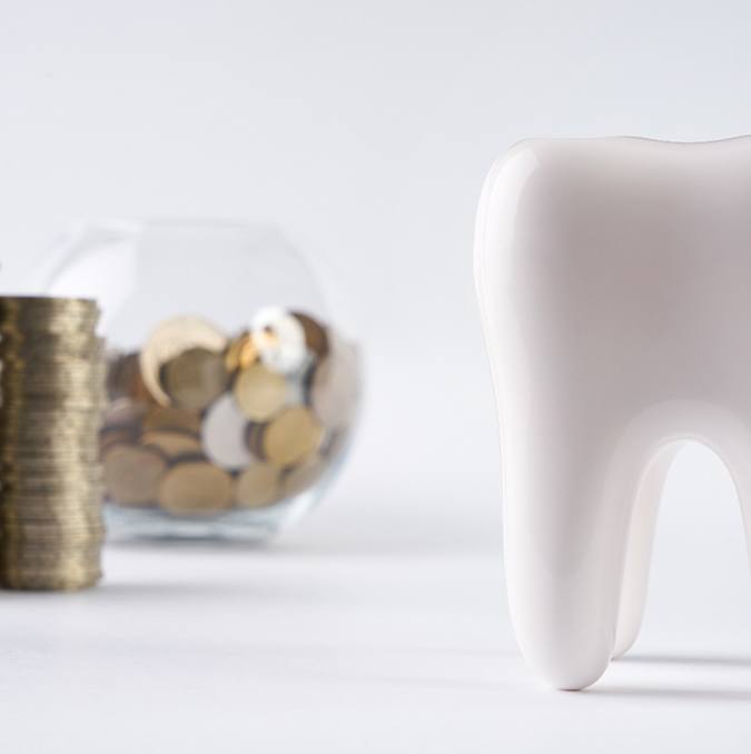 A tooth next to a bowl of coins