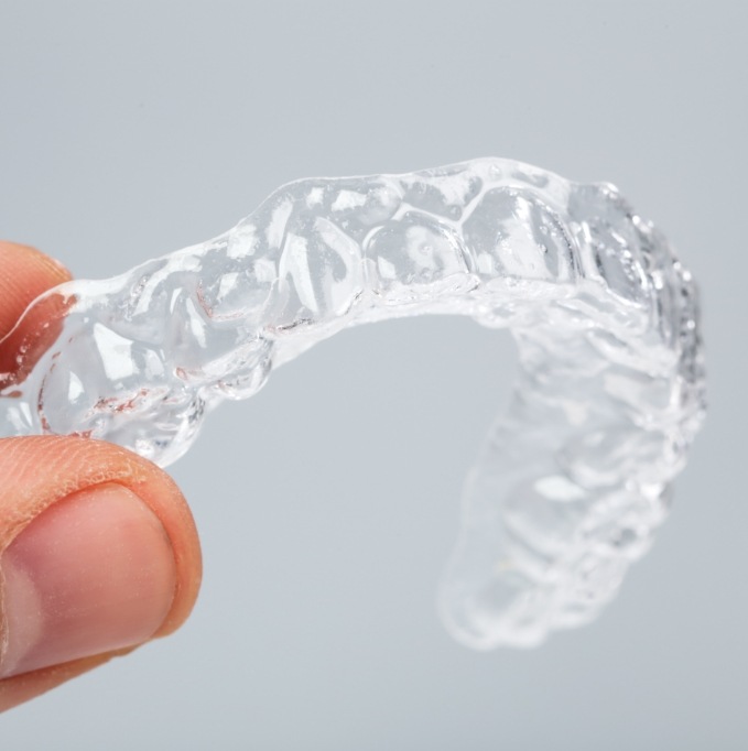 Close up of hand holding an Invisalign clear aligner