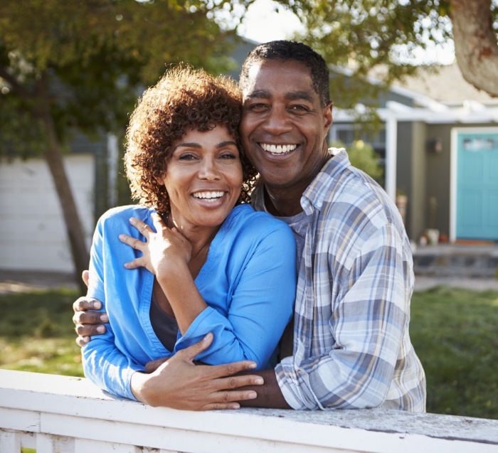 Smiling man and woman standing outside hugging