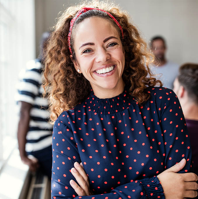 Woman in polka dot shirt smiling with arms folded