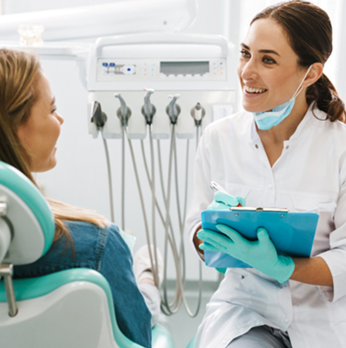 Dentist smiling while taking notes on clipboard