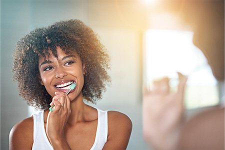 Woman smiling while brushing her teeth